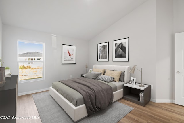 bedroom with high vaulted ceiling and light hardwood / wood-style floors