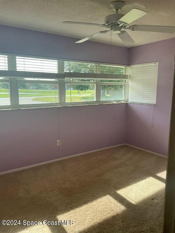 carpeted spare room featuring a textured ceiling and ceiling fan