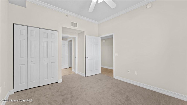 unfurnished bedroom with ornamental molding, light colored carpet, ceiling fan, and a closet