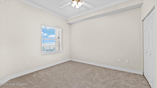 unfurnished bedroom featuring light colored carpet, ceiling fan, crown molding, and a closet