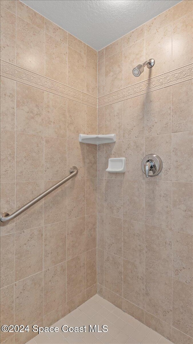 bathroom with a textured ceiling and tiled shower