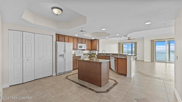 kitchen with sink, kitchen peninsula, dark stone counters, white appliances, and a raised ceiling