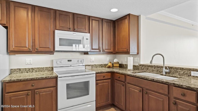 kitchen featuring stone counters, white appliances, sink, and a textured ceiling