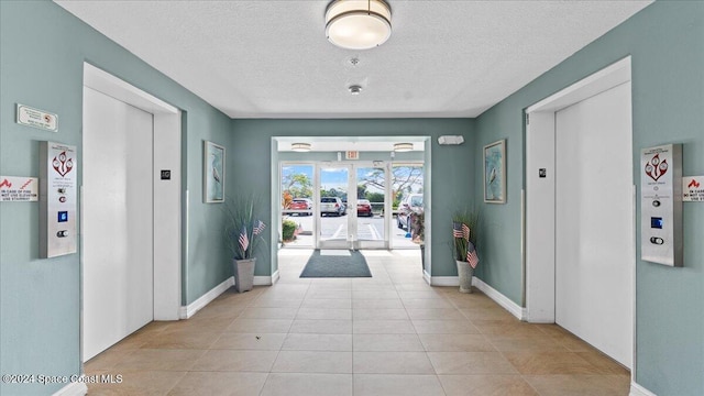 hall with french doors, a textured ceiling, elevator, and light tile patterned floors