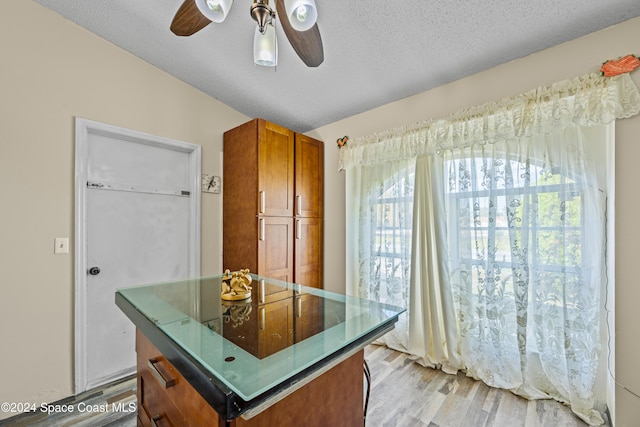 kitchen featuring a kitchen island, a textured ceiling, light hardwood / wood-style floors, lofted ceiling, and ceiling fan