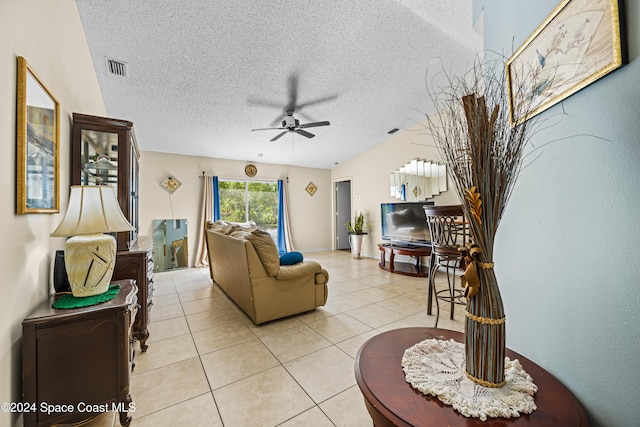 living room featuring a textured ceiling, light tile patterned floors, and ceiling fan