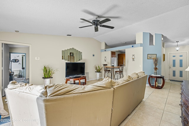 living room with vaulted ceiling, light tile patterned floors, ceiling fan, and a textured ceiling