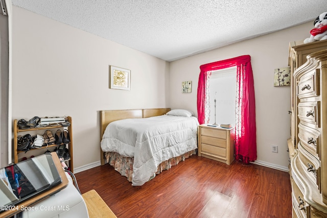 bedroom featuring a textured ceiling and dark hardwood / wood-style floors