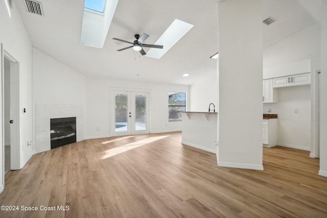 unfurnished living room featuring a tile fireplace, light hardwood / wood-style flooring, and french doors