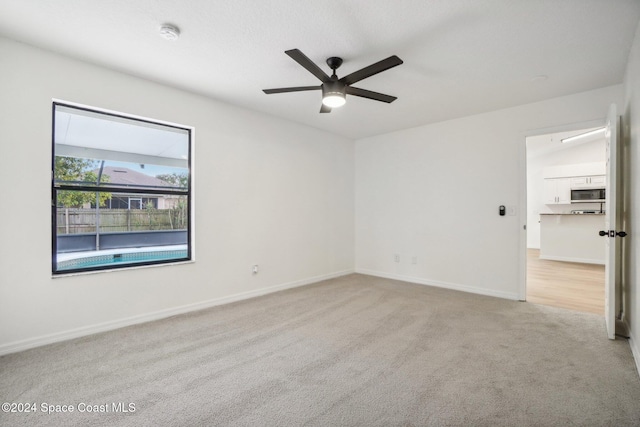 spare room featuring light colored carpet and ceiling fan