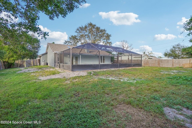 rear view of house featuring a lanai and a lawn