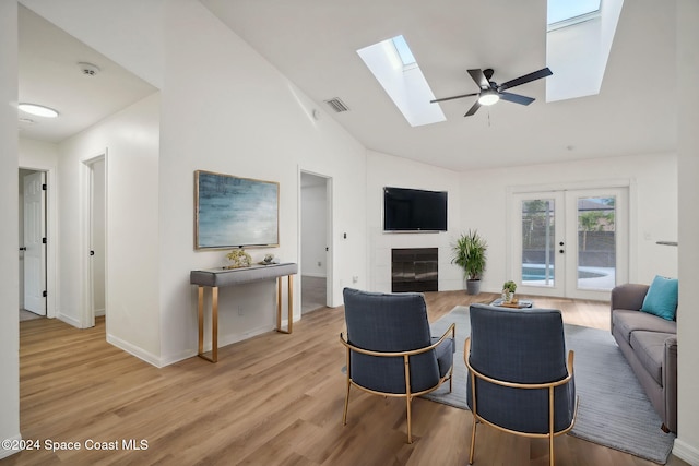 living room with french doors, light hardwood / wood-style flooring, ceiling fan, and vaulted ceiling