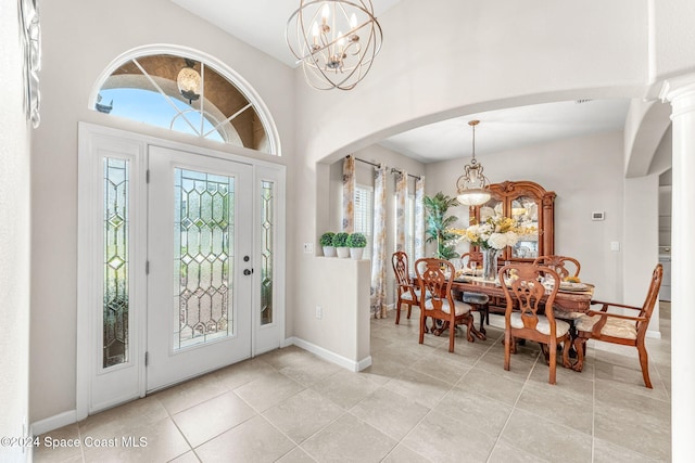 tiled entryway featuring decorative columns and a notable chandelier