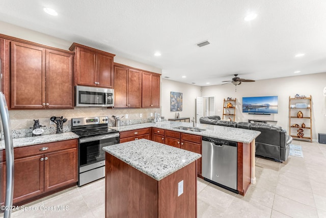 kitchen with stainless steel appliances, sink, tasteful backsplash, ceiling fan, and a kitchen island