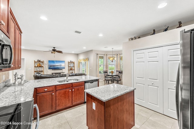 kitchen featuring light stone counters, a kitchen island, appliances with stainless steel finishes, sink, and ceiling fan