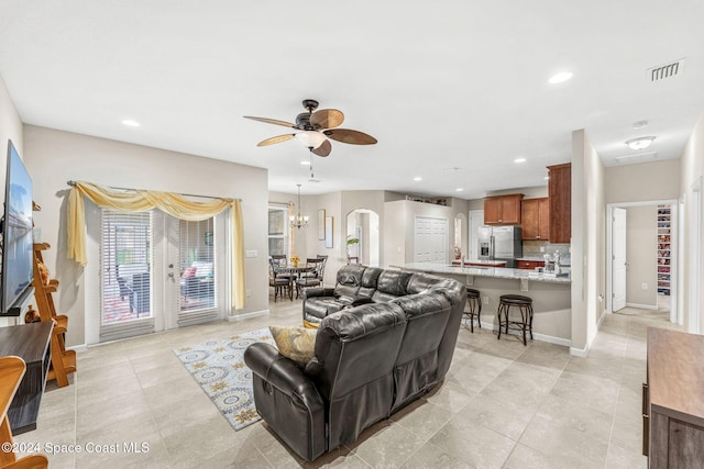 living room with ceiling fan with notable chandelier and light tile patterned floors