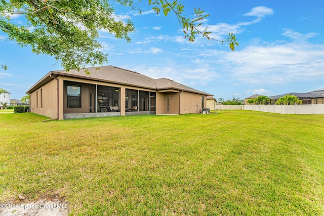 back of house with a sunroom and a lawn