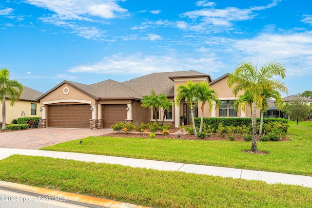 3540 Watergrass St, West Melbourne, FL 32904 - view of front facade with stucco siding, a garage, decorative driveway, a front lawn, and stone siding