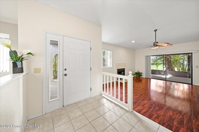 entryway with a fireplace, light hardwood / wood-style floors, and ceiling fan