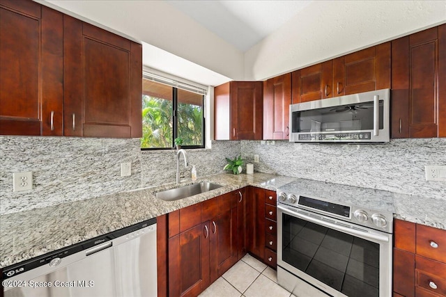 kitchen with tasteful backsplash, light stone counters, stainless steel appliances, light tile patterned floors, and sink