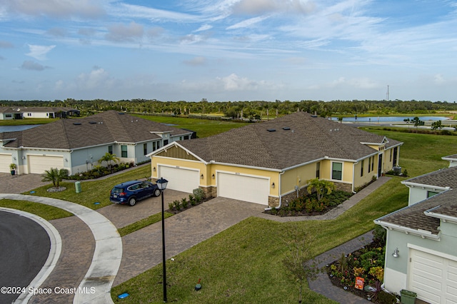 view of front of house with a front yard, a water view, and a garage