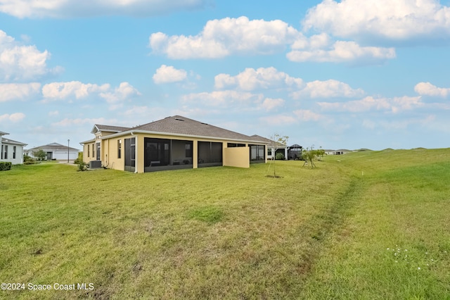 back of property with central AC, a sunroom, and a yard