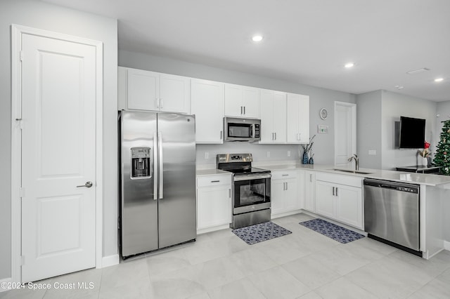 kitchen featuring appliances with stainless steel finishes, sink, light tile patterned floors, and white cabinets