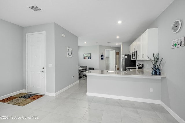 kitchen with white cabinets, kitchen peninsula, sink, light tile patterned flooring, and appliances with stainless steel finishes