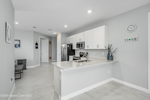 kitchen featuring kitchen peninsula, light tile patterned floors, sink, white cabinetry, and appliances with stainless steel finishes