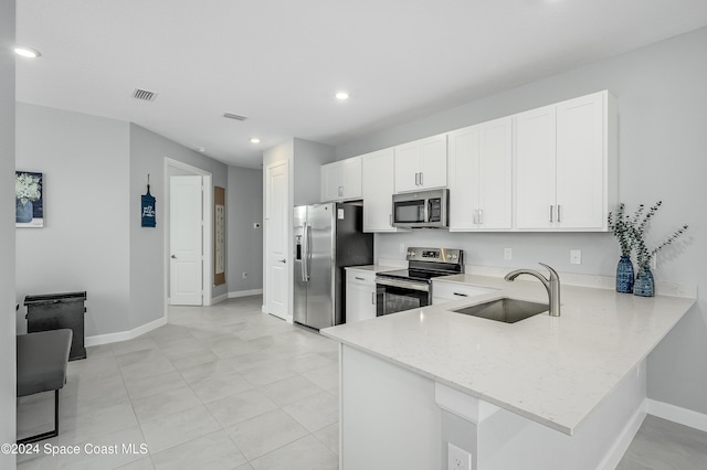 kitchen featuring light stone counters, appliances with stainless steel finishes, sink, white cabinets, and kitchen peninsula