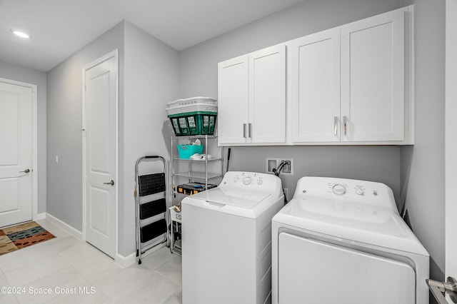 clothes washing area featuring washing machine and dryer, cabinets, and light tile patterned floors