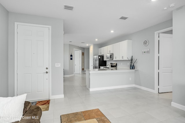 kitchen with stainless steel appliances, white cabinetry, sink, kitchen peninsula, and light tile patterned floors