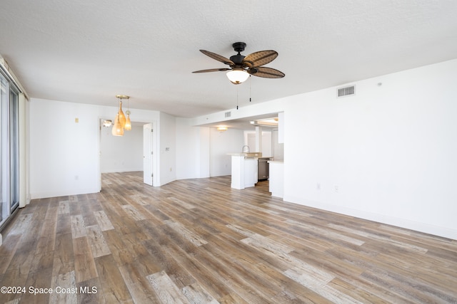 unfurnished living room with sink, a textured ceiling, ceiling fan, and light hardwood / wood-style flooring