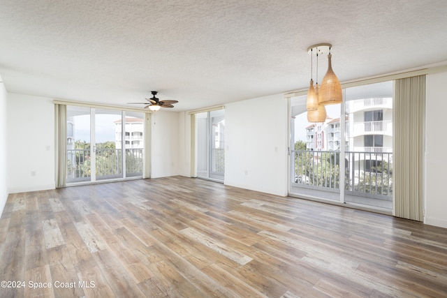 unfurnished living room with hardwood / wood-style flooring, ceiling fan, and a textured ceiling