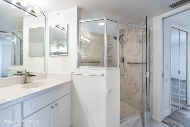 bathroom with hardwood / wood-style floors, vanity, and a shower with shower door