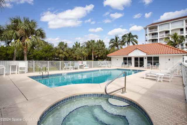 view of swimming pool featuring a hot tub and a patio