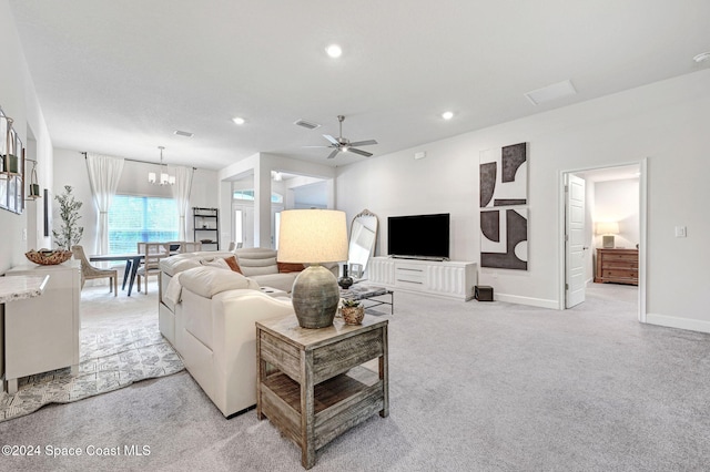 carpeted living room with ceiling fan with notable chandelier