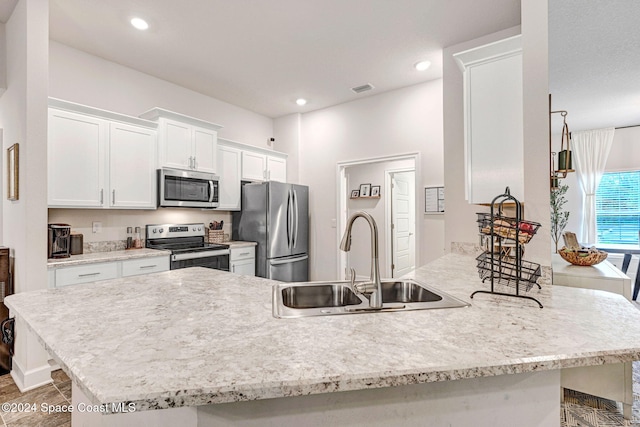 kitchen with a kitchen breakfast bar, white cabinetry, sink, and appliances with stainless steel finishes