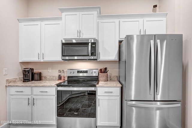 kitchen with light stone countertops, appliances with stainless steel finishes, and white cabinets