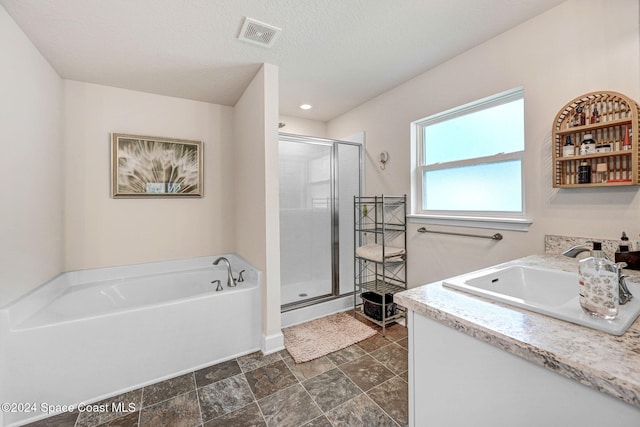 bathroom featuring shower with separate bathtub, vanity, and a textured ceiling