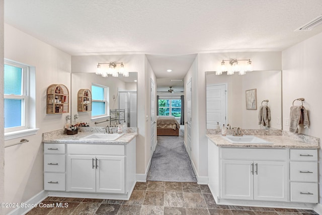 bathroom featuring vanity, ceiling fan, and a textured ceiling