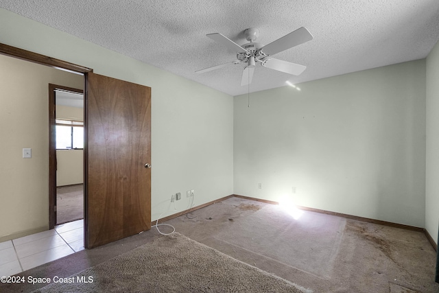 unfurnished room with ceiling fan, light colored carpet, and a textured ceiling