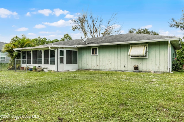 rear view of property featuring a yard and a sunroom