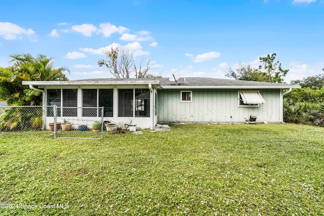 rear view of house featuring a sunroom and a yard