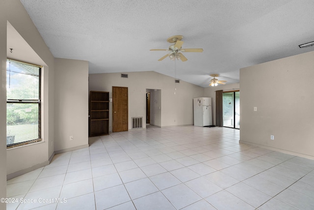 empty room featuring ceiling fan, light tile patterned floors, a textured ceiling, and vaulted ceiling