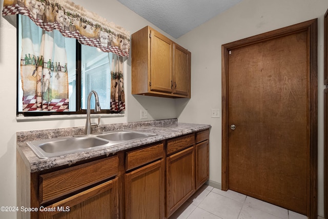 kitchen featuring a textured ceiling, light tile patterned flooring, and sink