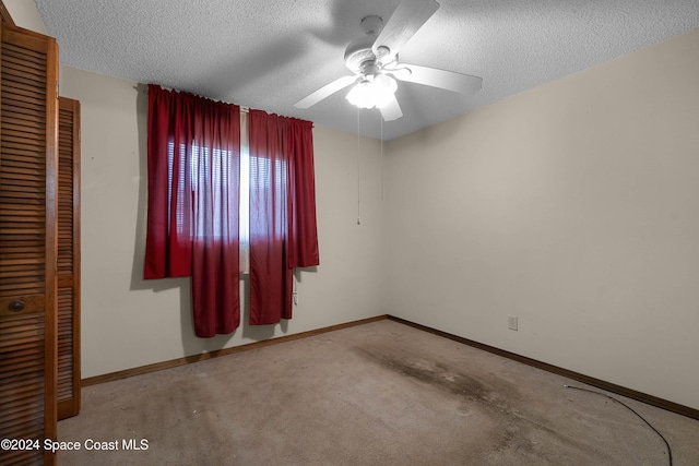 empty room featuring ceiling fan, light carpet, and a textured ceiling