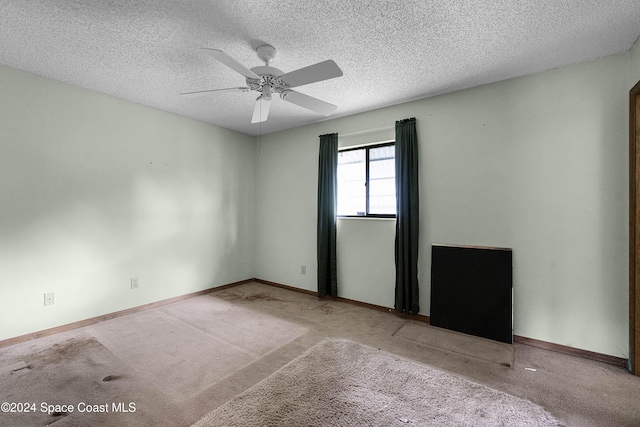 carpeted spare room with a textured ceiling and ceiling fan