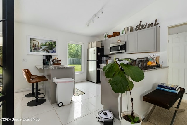 kitchen featuring gray cabinets, light tile patterned floors, appliances with stainless steel finishes, kitchen peninsula, and a breakfast bar area