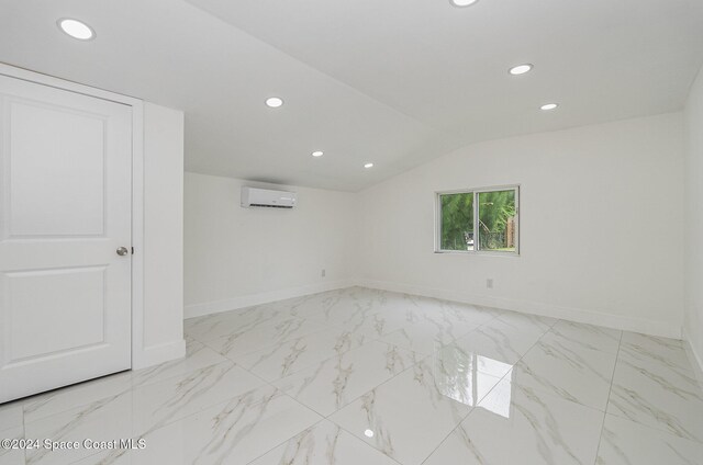 spare room featuring vaulted ceiling and a wall mounted air conditioner